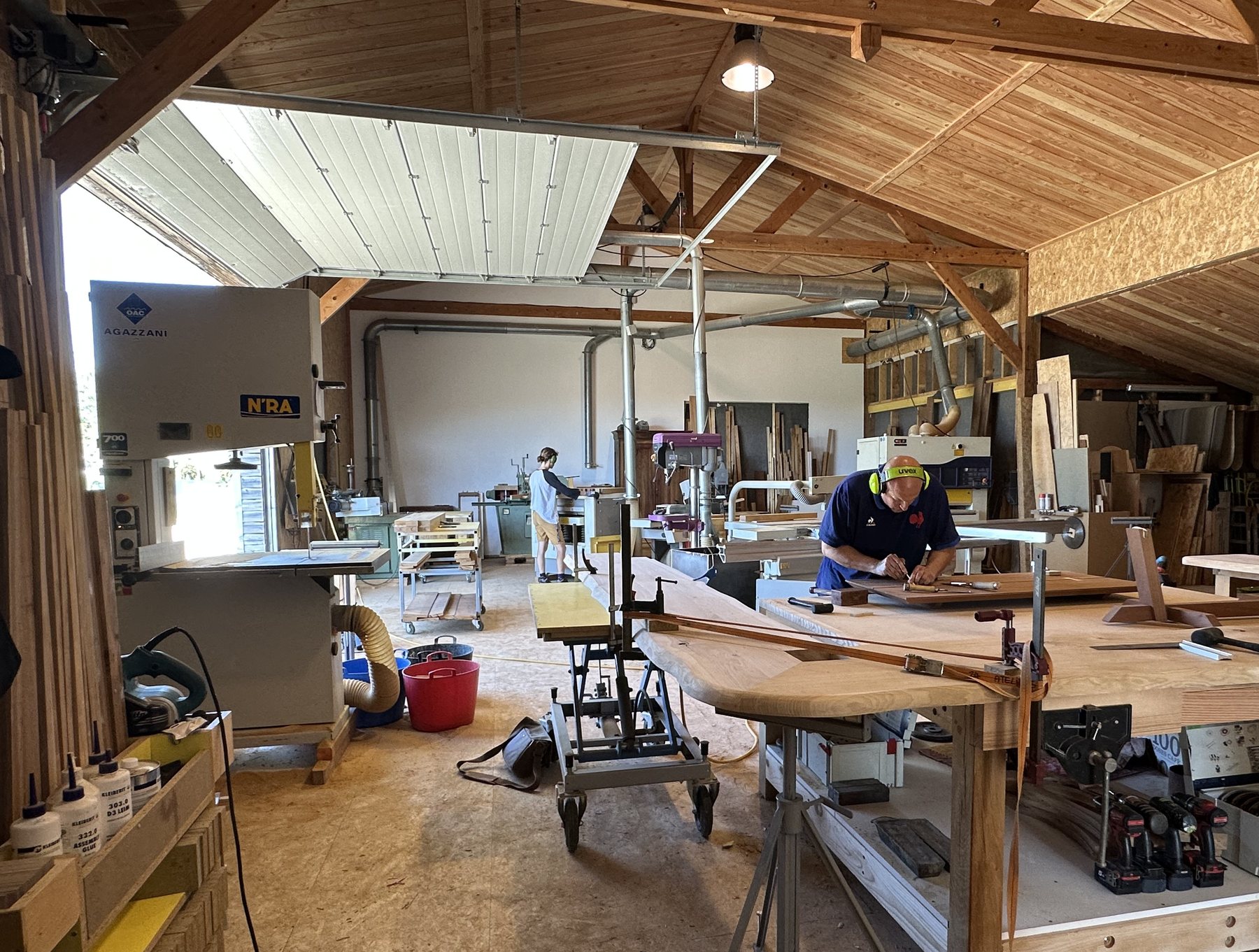 Intérieur de l'Atelier de Fabrication, artisans au travail sous la charpente en bois